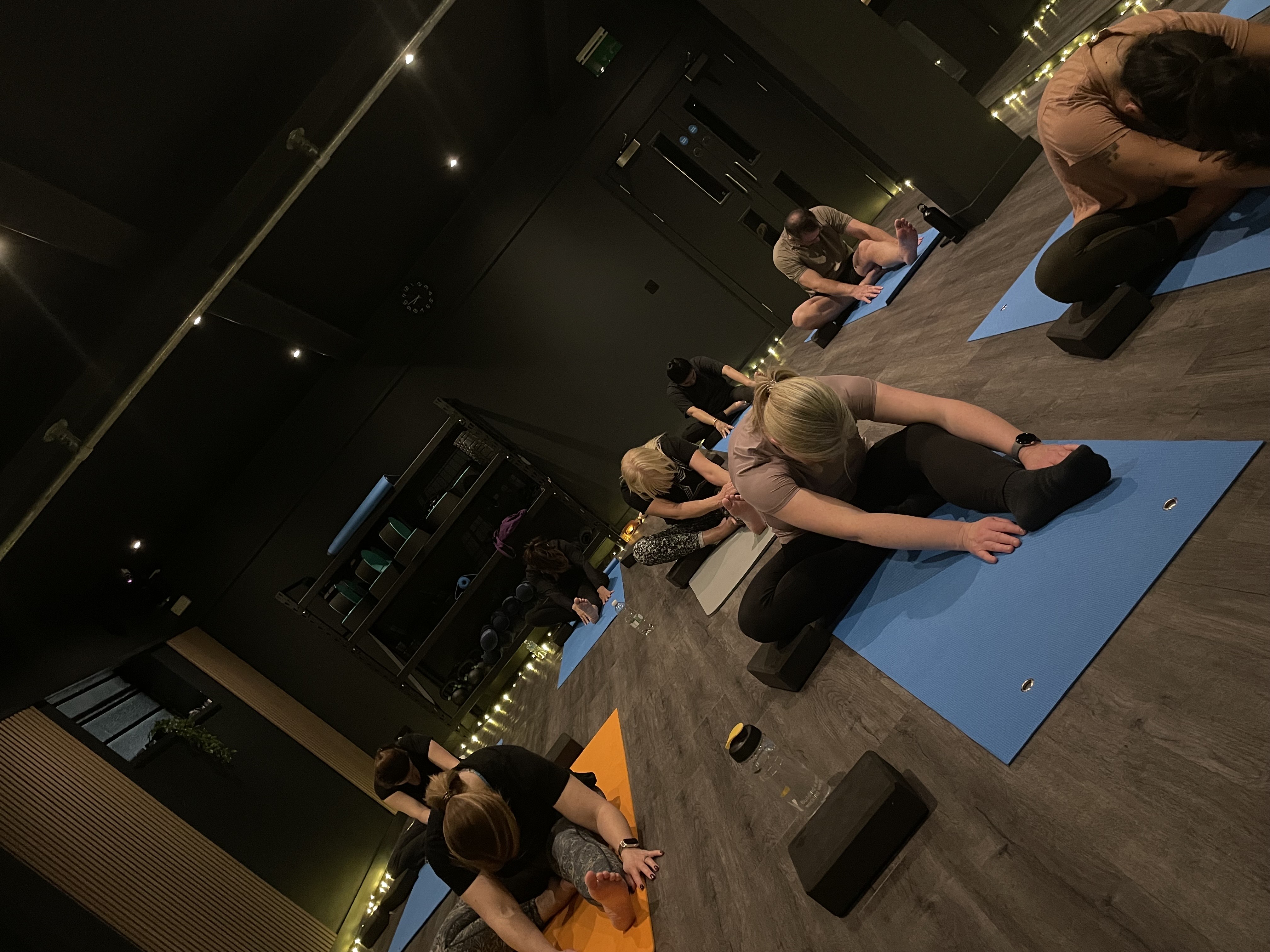 Moonlight Yoga, an evening class stretching forward with an orange mat in the foreground